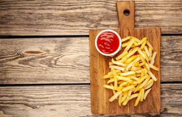 French fries with ketchup on wooden background