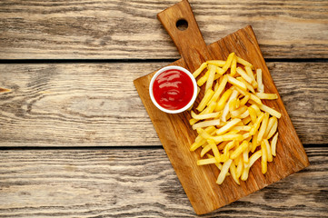 French fries with ketchup on wooden background