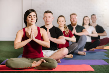 A group of young people sitting in yoga pose behind each other