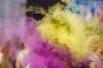 Young woman stands in colorful splashes or clouds of holi powder