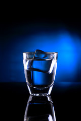 Shot Glass with an Ice Cube on Blue background