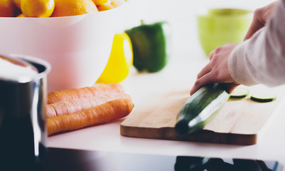 Cutting a cucumber on wooden board. Preparing meal of vegetables.