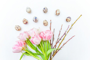 Spring greeting card. Easter eggs cotton willow branch and pink fresh tulip flowers bouquet on rustic white wooden background. Easter concept. Flat lay top view copy space. Spring flowers tulips
