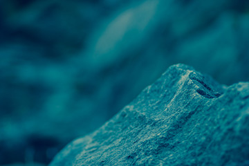 Granite rocks in blue-green tinting. Granite close up. Texture of the stone with blue color. Background from natural material with cool shades