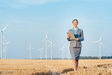 Frau investiert Geld ethisch und nachhaltig in Windkraft Windräder zur Stromerzeugung - obrazy, fototapety, plakaty