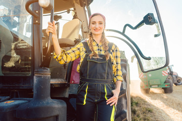 Bäuerin steht vor dem Traktor auf dem Kornfeld während der Ernte