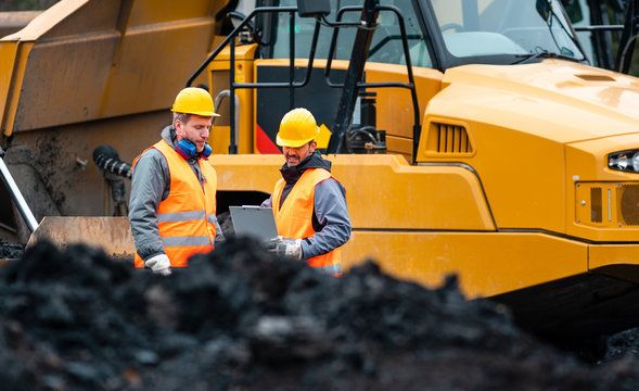 Arbeiter im Tagebau schauen auf einen Plan 
