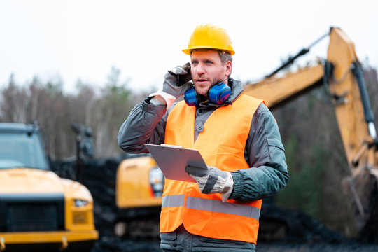Portr&auml;t eines Arbeiters im Tagebau vor einem Bagger