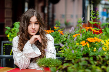 A young, beautiful, dark-haired woman sitting in a street cafe.