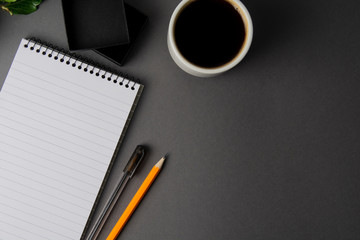 Creative flat lay of workspace desk. Top view office desk with notebooks and coffee cup on grey background. Top view with copy space. Minimalistic work space.