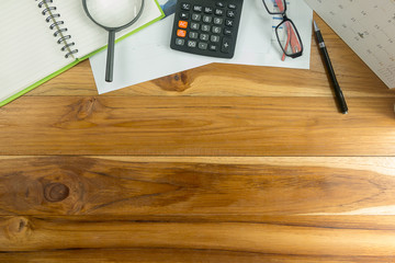 Top view of a wooden desk color with a computer graph, magnifier and office business calculator.