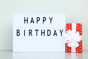 Lightbox with words Happy Birthday and red gift box on grey background