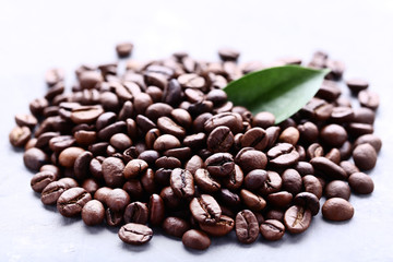 Coffee beans with green leafs on grey wooden table