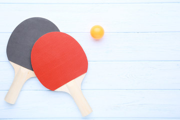 Table tennis rackets with ball on wooden table