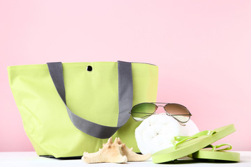 Summer bag with flip flops and towel on pink background