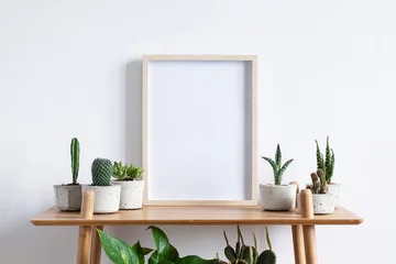 Photo sur Plexiglas Cactus Stylish room interior with mock up photo frame on the brown bamboo shelf with beautiful plants in differents hipster and design pots. White walls. Modern and floral concept of shelfs.