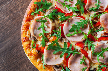 Pizza with Mozzarella cheese, mushrooms, ham, tomato sauce, pepper, Spices and Fresh arugula. Italian pizza on wooden table background 