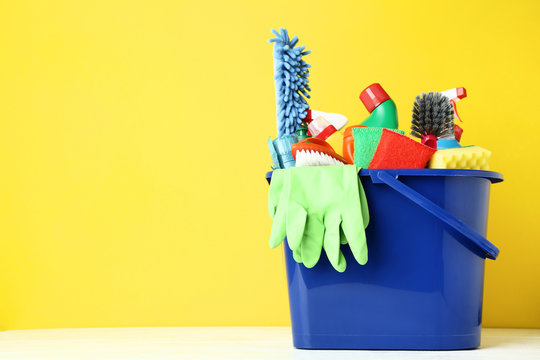 Bottles With Detergent And Cleaning Tools On Yellow Background