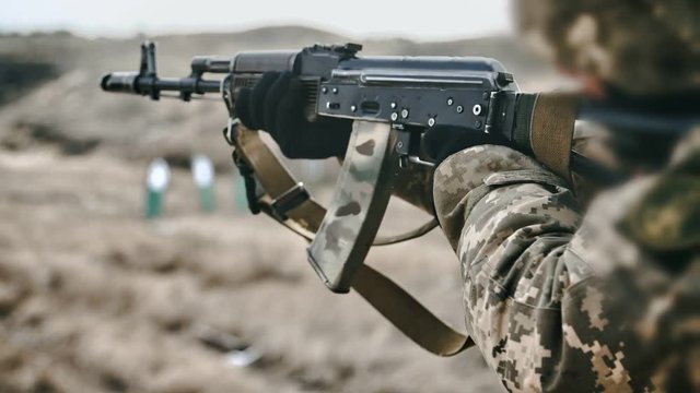 Man shooting from AK 74M and targeting in a bullseye in a field in slo-mo 