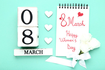 Wooden calendar with hearts and text Happy Women's Day in notepad