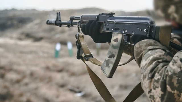 Man shooting from AK 74 with a muzzle device venting propellant gasses in slo-mo    