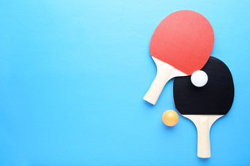 Table tennis rackets with balls on blue background