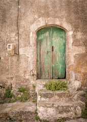 Wooden doors in green color with weathered paint and stone steps before it on the island Kyhtira, Greece