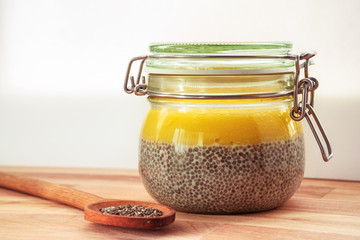 Chia pudding with mango in glass jar on wooden cutboard against white background. Healthy food concept. Raw, vegan