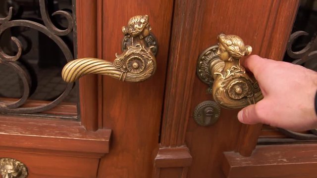 A man s hand opens the door, a close-up photo. The hand holds onto the antique metal handle he doorman opens the hotel