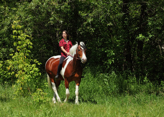 Beautiful cowgirl bareback ride her horse in woods glade at sunset