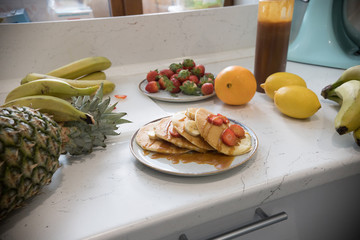 A person serving sweet pancakes with fresh fruits