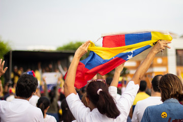 Woman vigorously holding Venezuelan flag at protest against Nicolas Maduro - obrazy, fototapety, plakaty
