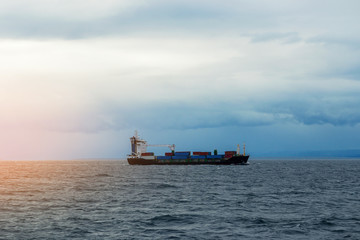 Cargo ship barge with containers on the sea horizon at sunset