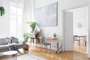 Foto op Plexiglas Stylish scandinavian open space with design furniture, plants, bamboo bookstand and wooden desk. Brown wooden parquet. Abstract painting. Modern decor of bright room next to dining room.  © FollowTheFlow