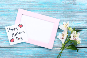 Greeting card with alstroemeria flowers and blank frame on blue wooden table