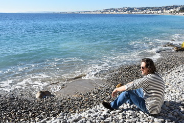 seaman sitting on beach and looking at the sea