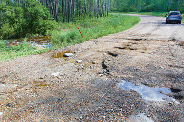 A washed out gravel road with a vehicle in the background