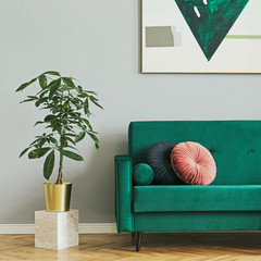 Luxury home interior with green velvet design sofa, pillows, tropical plant on the stand and...