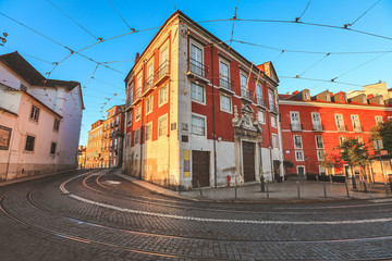 Fototapeta na wymiar View of traditional old street and colorful buildings in the morning with tram tracks in Lisbon. Alfama district. Portugal.