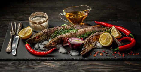 Fresh pikes with spices, ice and greens on a gray background. Top view with copy space