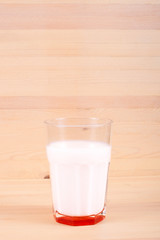 A large glass of milk on a wooden table. Dairy product