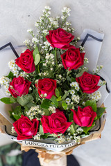 Colorful bouquet of fresh flowers against brick wall. Bunch of orchids, roses, freesia and eucalyptus leaves. Rustic flower background.love, valentines day and holidays concept - close up of red roses