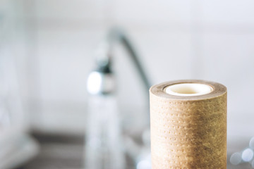 Dirty, brown, used water filter cartridges on background of the sink and tap with water, selective focus