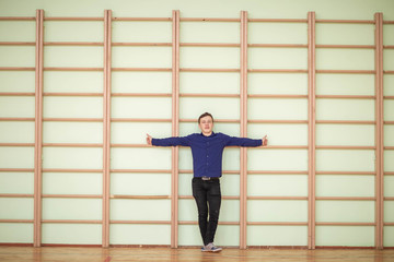 the guy in the blue shirt, black jeans and sneakers on the background of the wall bars in the school gym