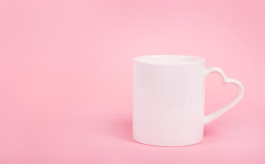 Mug with heart on pink background. Valentine's day holiday. White mug. White cup. Copy space.
