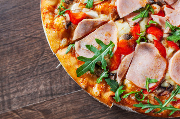 Pizza with Mozzarella cheese, mushrooms, ham, tomato sauce, pepper, Spices and Fresh arugula. Italian pizza on wooden table background