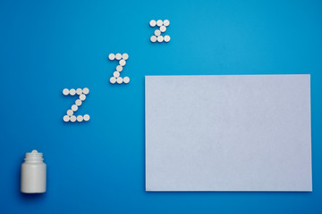 Fototapeta premium white pills in Z shape. Sleeping pills on blue background. Space for text
