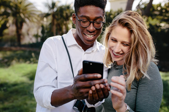 Smiling multiracial couple looking at pictures on phone