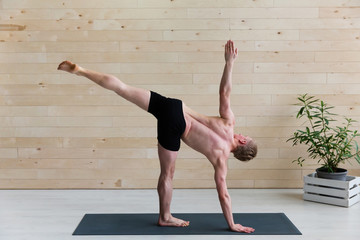 Sporty man practicing yoga on yoga class
