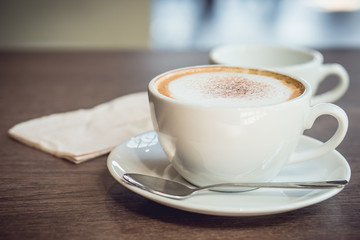 Hot coffee and hot tea place on the wooden table in early morning with copyspace, white cup and silver spoon.